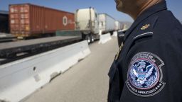 A U.S. Customs and Border Protection (CBP) officer stands next to a line of trucks entering from Mexico at the Otay Mesa Cargo Port of Entry in San Diego, California, U.S., on May 23, 2017. The skirmish among House Ways and Means Committee Republicans over a border tax provision resurfaced during a May 24 hearing where Treasury Secretary Steven Mnuchin was testifying on the president's proposed fiscal year 2018 budget. Photographer: David Maung/Bloomberg via Getty Images