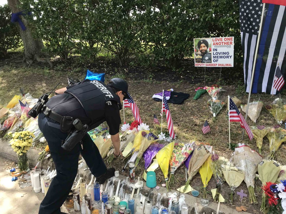 A law enforcement officer visits a makeshift memorial set up for Deputy Sandeep Dhaliwal.
