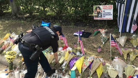 A law enforcement officer visits a makeshift memorial set up for Deputy Sandeep Dhaliwal.