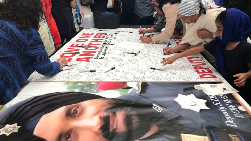 Mourners sign a banner dedicated to Dhaliwal on Wednesday, in a hall near the arena where the funeral is being held.