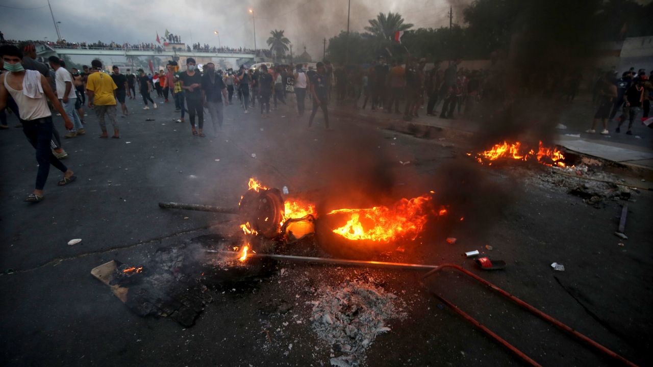 Iraqi protesters stand next to burning tyres during a demonstration in Baghdad on October 2, 2019.