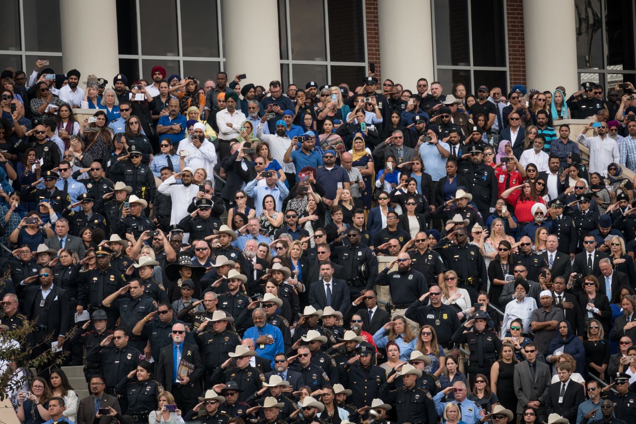 Law enforcement personnel salute as the casket is moved toward a waiting hearse following the funeral services.