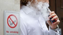 A smoker is engulfed by vapours as he smokes an electronic vaping machine during lunch time in central London on August 9, 2017.