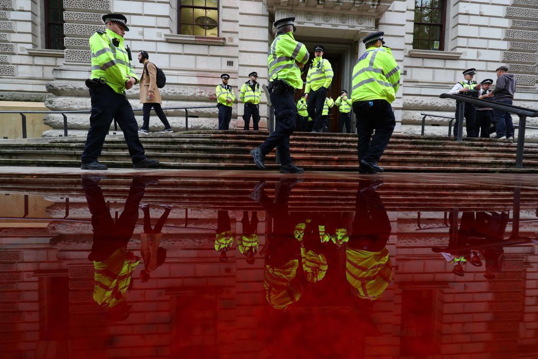 Police officers stand next to a pool of fake blood outside Britain's finance ministry.