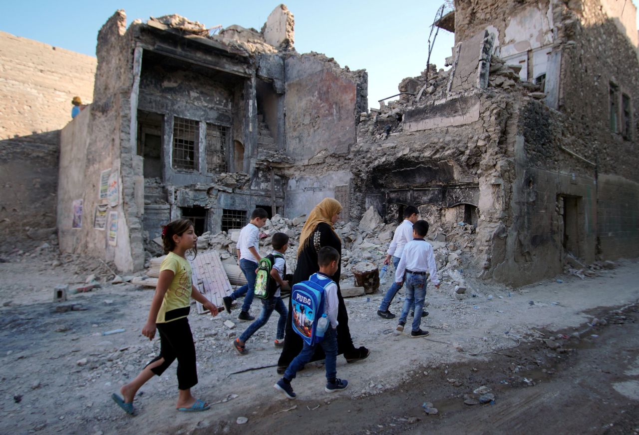 A woman in Mosul, Iraq, walks with her kids on the first day of school on Tuesday, October 1.