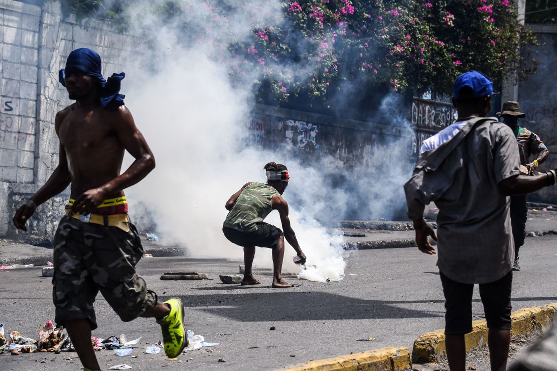 A demonstrator douses a tear gas canister with water during a protest demanding the resignation of President Jovenel Moise in Port-au-Prince on September 27, 2019.