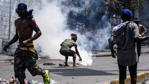 A demonstrator douses a tear gas canister with water during a protest demanding the resignation of President Jovenel Moise in Port-au-Prince on September 27, 2019.
