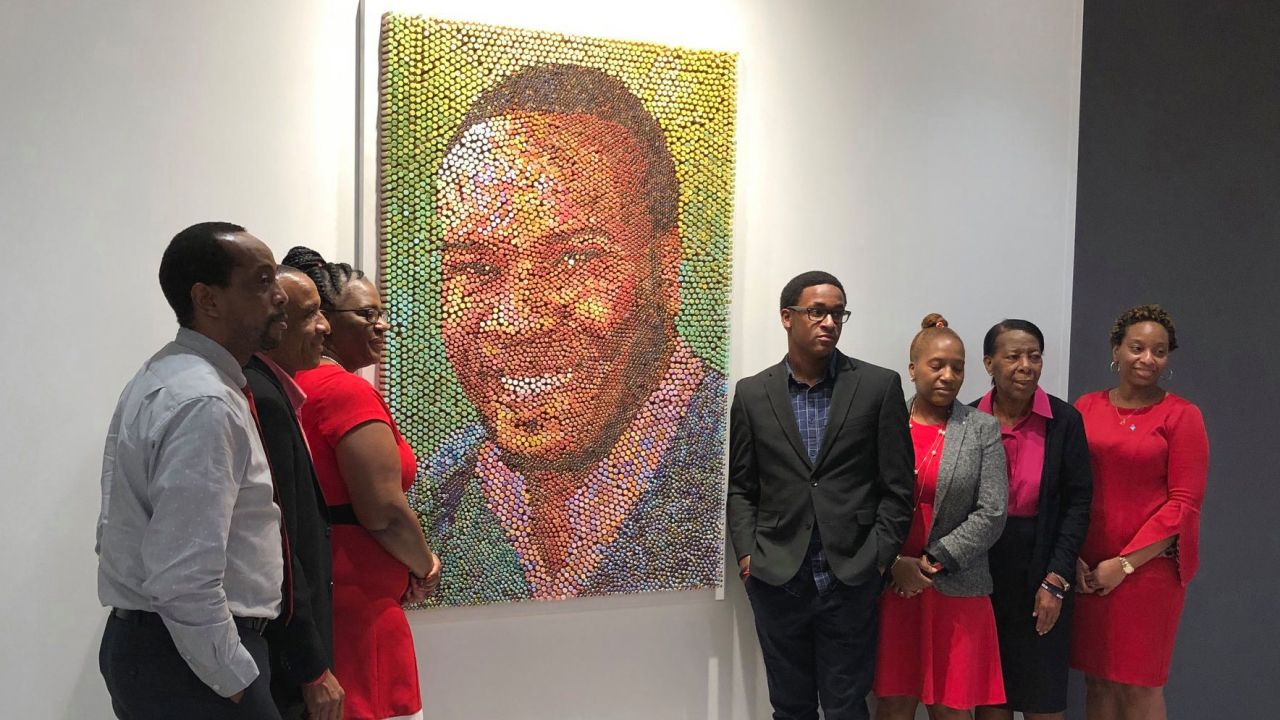 Members of Botham Jean's family pose with his portrait at PricewaterhouseCooper's Dallas office.
