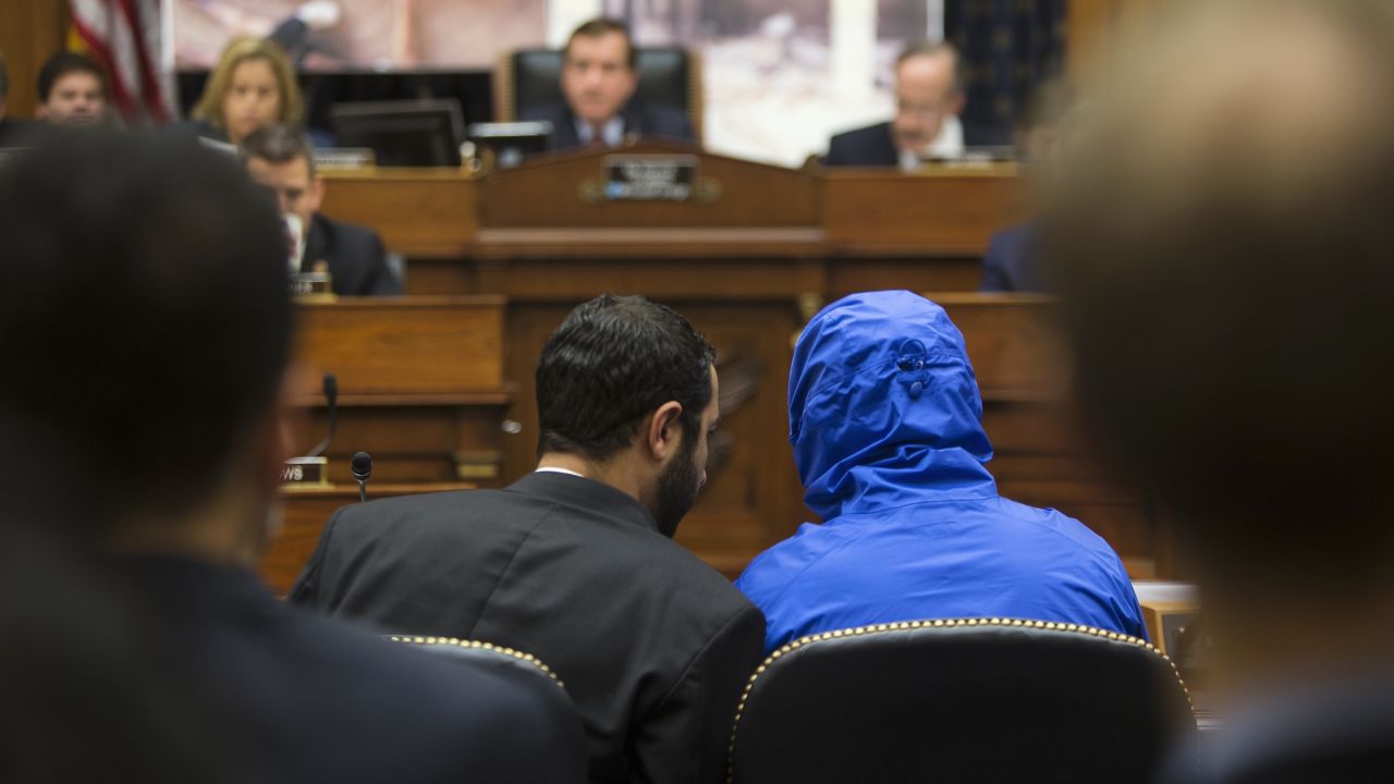 Syrian defector Caesar conceals his identity as he listens with a translator to the House Foreign Affairs Committee in 2014.