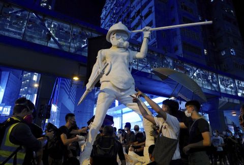 Protesters move a statue depicting a protester armed with gas mask, helmet and umbrella on the streets of Hong Kong on October 4.