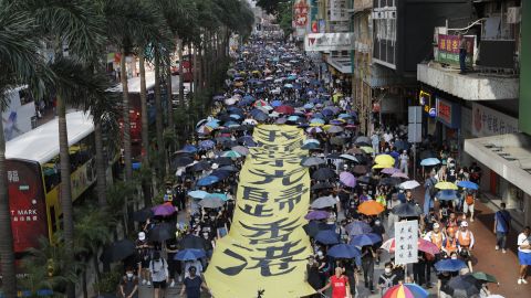 Protesters walk next to a banner with the words "May Glory be to Hong Kong" in Hong Kong on Saturday, October 5.