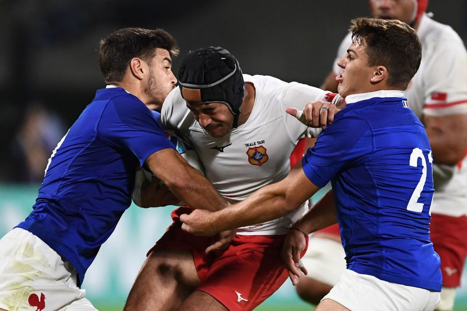 Tonga's centre Mali Hingano (C) is held up by France's  fly-half Romain Ntamack (L) and France's scrum-half Antoine Dupont (R).