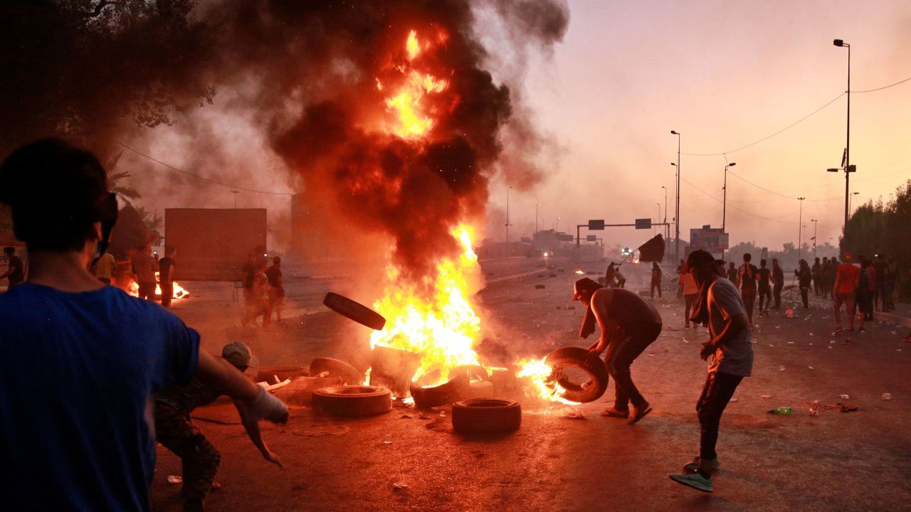 Iraqi security forces fire tear gas while anti-government protesters set fires in Baghdad on October 5.