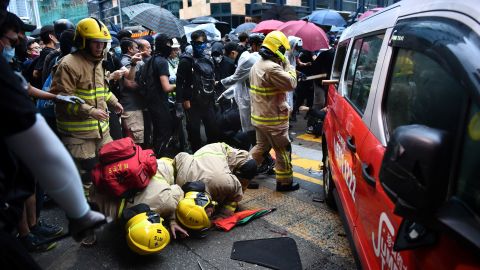 Rescue personnel check the bottom of a taxi after the driver allegedly drove onto the pavement, hitting protesters in Hong Kong on October 6.