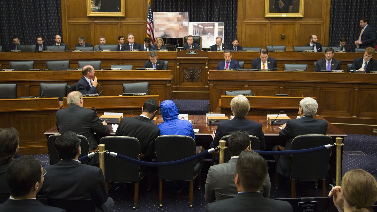 "Caesar," the man credited with smuggling out 50,000 photos said to document Syrian government atrocities, listens to his interpreter as he prepares to speak at a US Congressional briefing in July 2014.