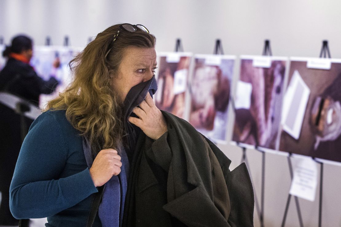 A woman reacts as she looks at a gruesome collection of Caesar's images at the United Nations Headquarters in New York.