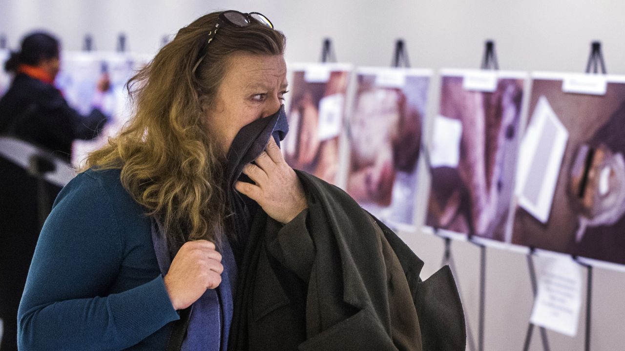 A woman reacts as she looks at a gruesome collection of Caesar's images at the United Nations Headquarters in New York.