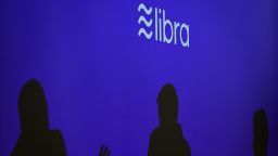 Silhouettes are seen beneath a sign of Libra, the cryptocurrency project launched by Facebook during a conference at marketing and communication school CREA in Geneva on September 26, 2019.        (Photo credit should read FABRICE COFFRINI/AFP/Getty Images)