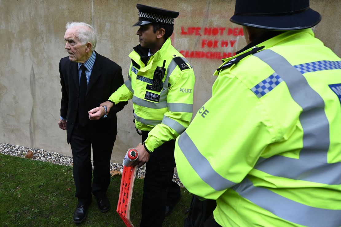 Police officers detain climate change activist Phil Kingston outside the UK Treasury.
