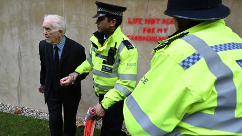 Police officers detain climate change activist Phil Kingston outside the UK Treasury.