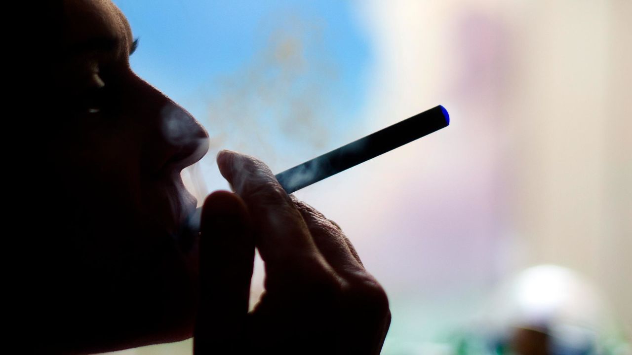 This September 25, 2013 photo illustration taken in Washington, DC, shows a woman smoking an "Blu" e cigarette. The National Association of Attorneys General on September 24, issued a letter urging the US Food and Drug Administration to clamp down on the fast-growing e-cigarette market, saying manufacturers are enticing teenagers to smoke with cartoon characters, television ads and bubble-gum flavors.  (Photo credit should read JIM WATSON/AFP/Getty Images)