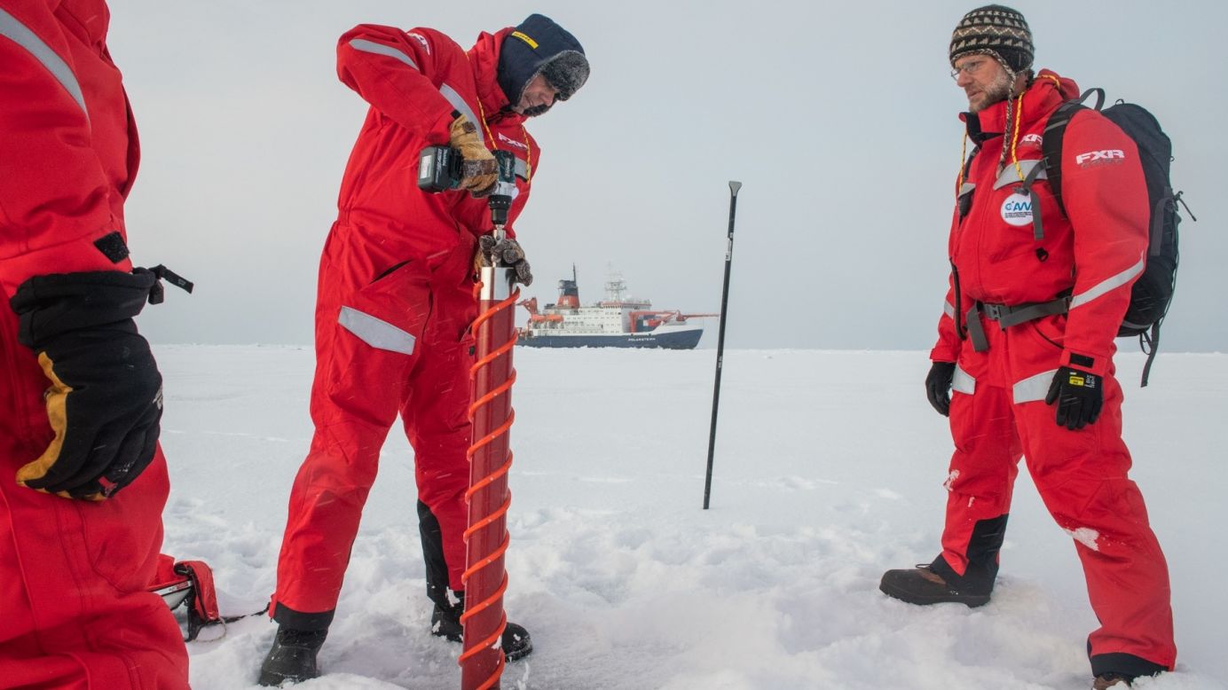 Scientists Gunnar Spreen and Matthew Shupe drill into sea ice on September 30 with the MOSAiC expedition vessel Polarstern in the back on shot.