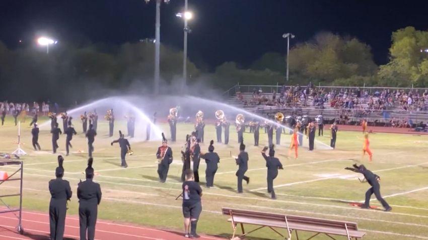 marching band plays in sprinklers