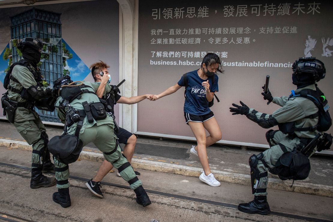 Police chase down a couple wearing facemasks in the central district in Hong Kong on October 5, 2019.