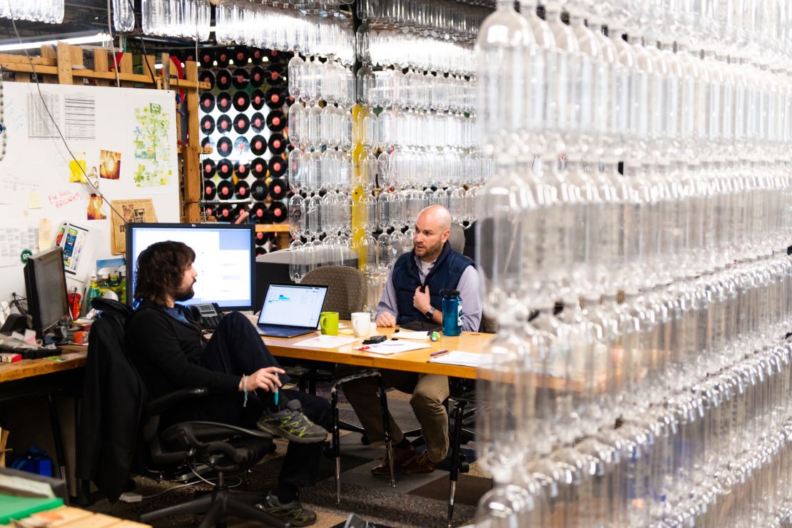 Szaky, left, speaks with a coworker in his office. Recycled plastic bottles form a curtain that walls off his office at the TerraCycle headquarters in Trenton, New Jersey. (Mark Kauzlarich for CNN)