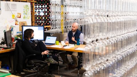 Szaky, left, speaks with a coworker in his office. Recycled plastic bottles form a curtain that walls off his office at the TerraCycle headquarters in Trenton, New Jersey. (Mark Kauzlarich for CNN)