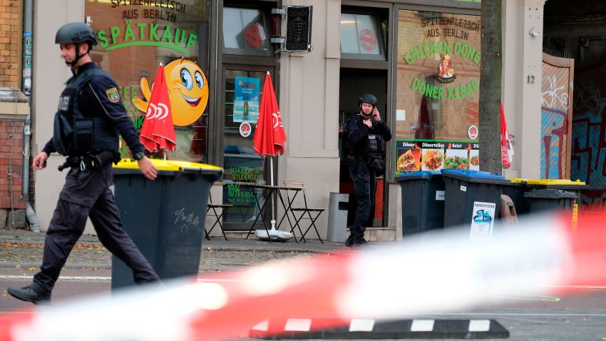 A police officer walks in front of a kebab grill in Halle, Germany, Wednesday, Oct. 9, 2019. A gunman fired several shots on Wednesday in the German city of Halle. Police say a person has been arrested after a shooting that left two people dead. (Sebastian Willnow/dpa via AP)
