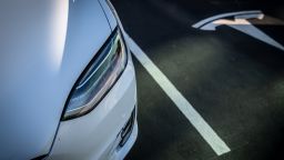A Tesla logo marks an empty parking bay next to a Model X electric vehicle.