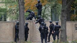 Policemen climb over a wall close to the site of a shooting in Halle an der Saale, eastern Germany, on October 9, 2019. - At least two people were killed in a shooting on a street in the German city of Halle, police said, adding that the perpetrators were on the run. "Early indications show that two people were killed in Halle. Several shots were fired. The suspected perpetrators fled in a car," said police on Twitter, urging residents in the area to stay indoors. (Photo by Sebastian Willnow / dpa / AFP) / Germany OUT (Photo by SEBASTIAN WILLNOW/dpa/AFP via Getty Images)