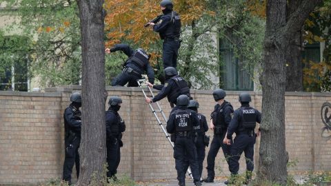 Policemen climb over a wall close to the site of a shooting in Halle, eastern Germany.