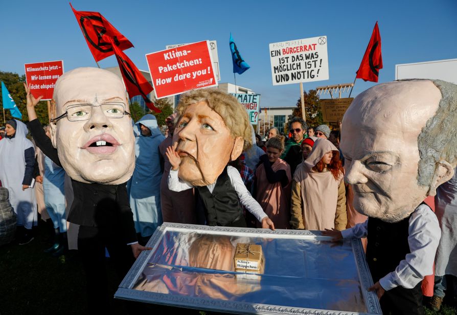 Extinction Rebellion protesters wear masks in Berlin on October 9. From left, the masks represent German Economy Minister Peter Altmaier, German Chancellor Angela Merkel and German Vice Chancellor Olaf Scholz.