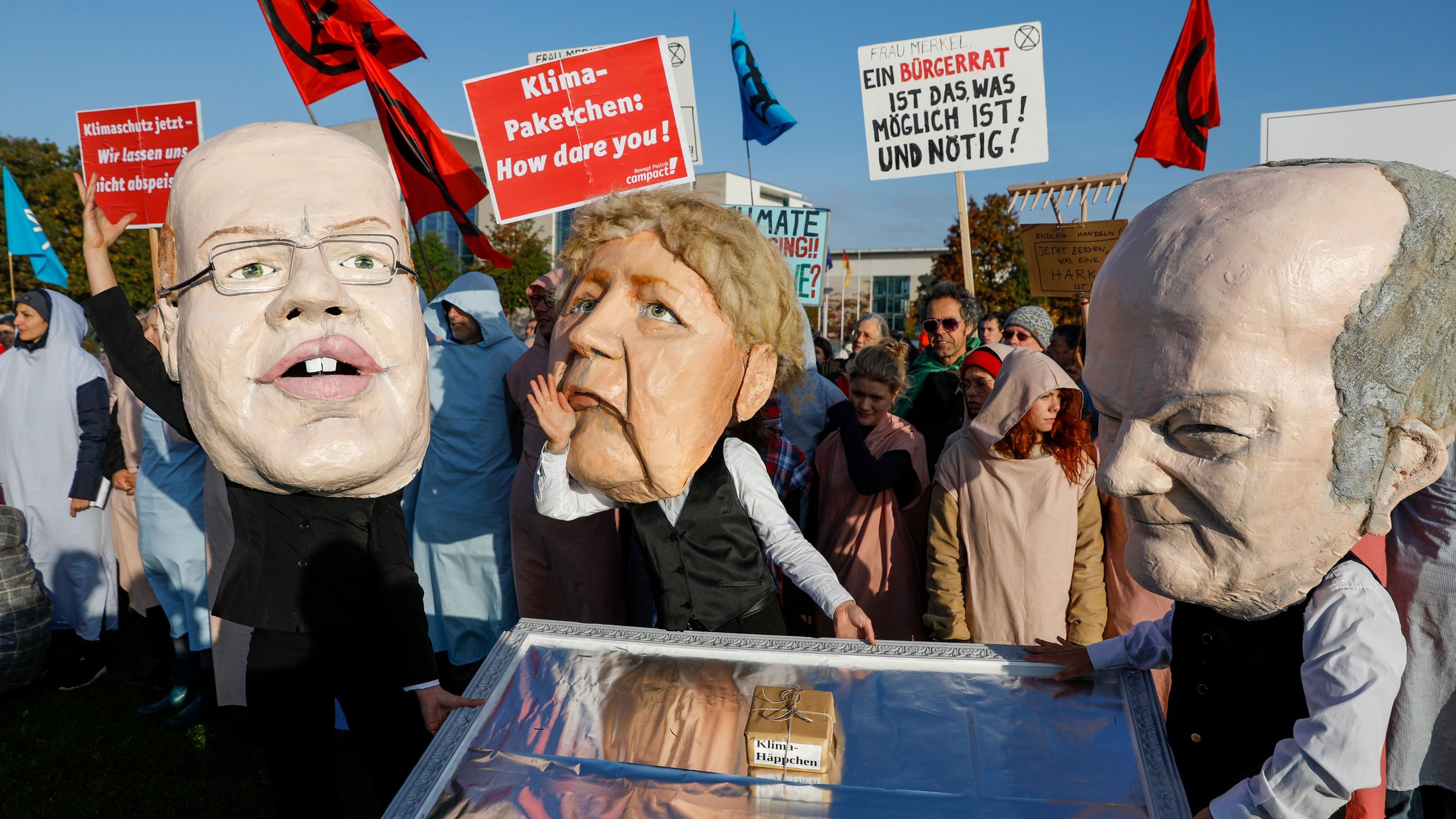 Extinction Rebellion protesters wear masks in Berlin on October 9. From left, the masks represent German Economy Minister Peter Altmaier, German Chancellor Angela Merkel and German Vice Chancellor Olaf Scholz.