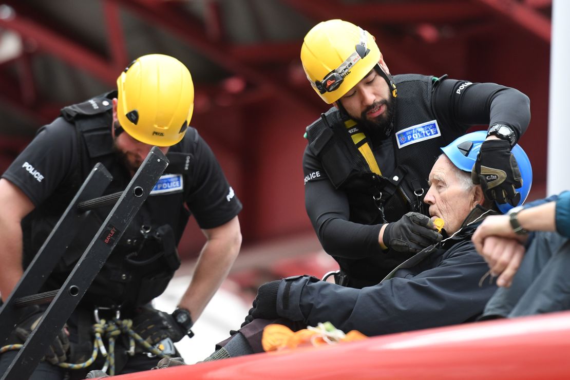 Police prepare to remove a climate change activist from the roof of a DLR train at Canary Wharf station.