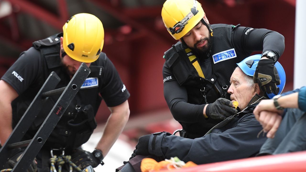 Police prepare to remove a climate change activist from the roof of a DLR train at Canary Wharf station.