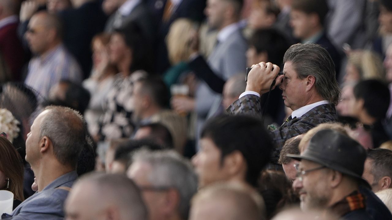 Racegoer David van der Hoeven watches the action through binoculars.