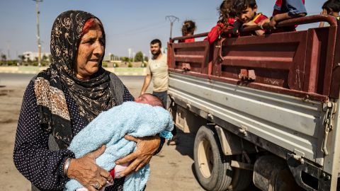 A woman holds a baby after arriving in Tal Tamr.