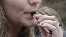 FILE - In this April 11, 2018, file photo, a high school student uses a vaping device near a school campus in Cambridge, Mass. Schools have been wrestling with how to balance discipline with treatment in their response to the soaring numbers of vaping students. Using e-cigarettes, often called vaping, has now overtaken smoking traditional cigarettes in popularity among students, says the Centers for Disease Control and Prevention. Last year, one in five U.S. high school students reported vaping the previous month, according to a CDC survey. (AP Photo/Steven Senne, File)  