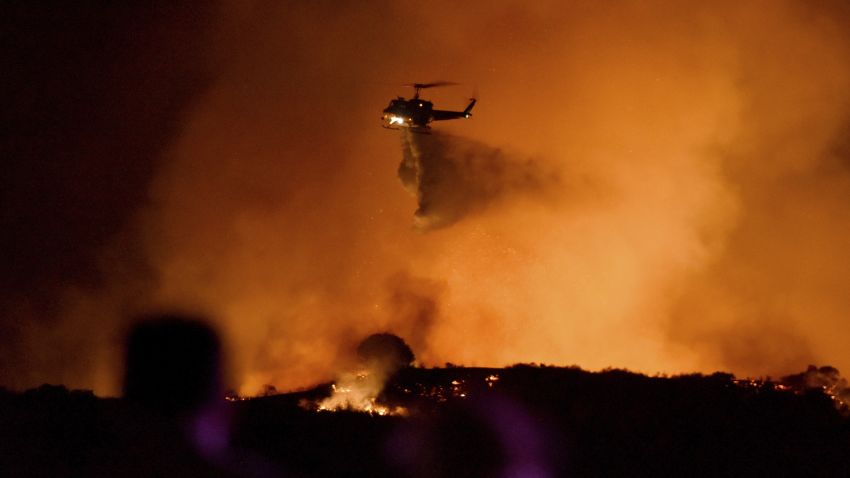A helicopter drops water on a brushfire in the Santa Monica Mountains in Newbury Park, Calif., Thursday, Oct. 10, 2019. Fire danger is high throughout California after the typically dry summer and early fall.  (AP Photo/Michael Owen Baker)