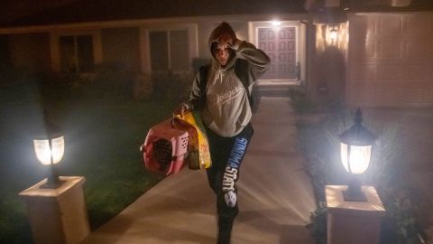 A woman leaves her home with her cat as the Saddleridge Fire threatens homes in Los Angeles' Granada Hills area on Friday.