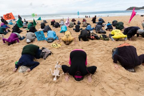 Activists bury their heads in the sand on Sydney's Manly Beach on October 11.