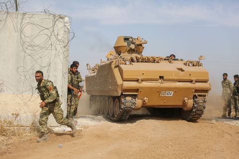 Pro-Turkish Syrian fighters drive an armored personnel carrier across the border into Syria on October 11.