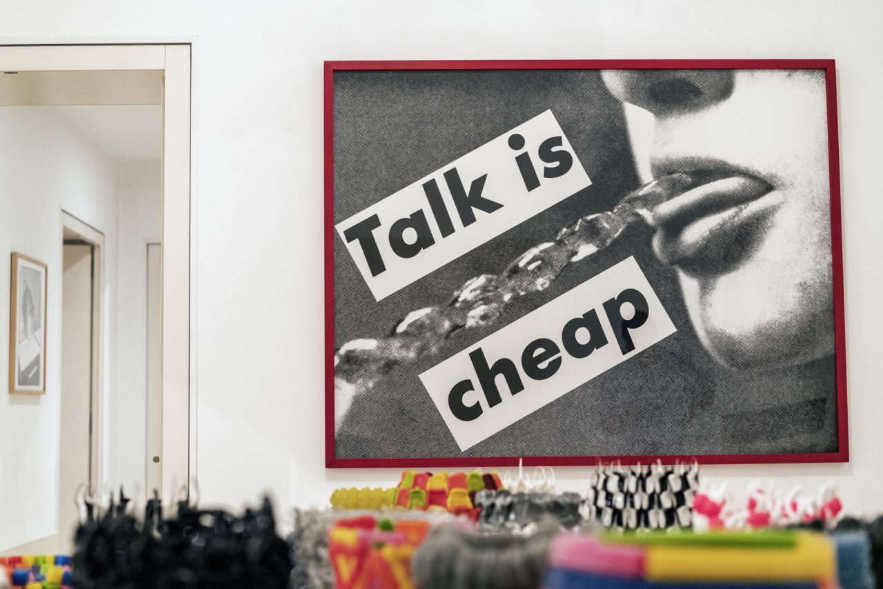 A work by Barbara Kruger titled "Talk is Cheap" (1985) hangs on a wall.