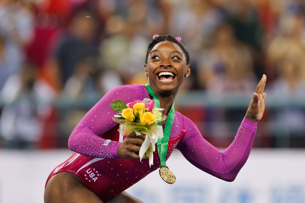 Biles dodges a bee flying near her during the medal ceremony after winning gold in the all-around final of the 2014 World Championships.
