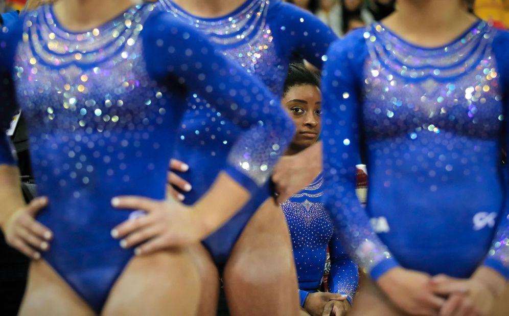 Biles rests behind teammates during qualifying sessions for the 2018 World Championships in Doha, Qatar.