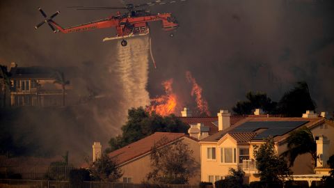 A helicopter drops water while battling the Saddleridge fire in northern Los Angeles on Friday.