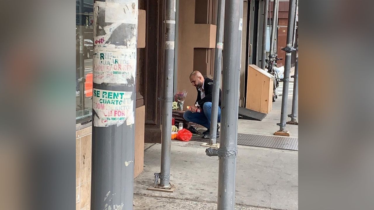 Hakki Akdeniz kneels at a memorial to the four homeless men killed in New York's Chinatown neighborhood on October 5.